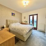 Modern bedroom with double bed and balcony view.