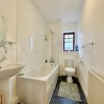 Modern bathroom with white fixtures and window.