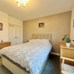 Modern bedroom with double bed and wooden furniture.