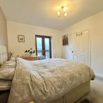 Bright bedroom with double bed and balcony view.