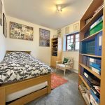 Cosy small bedroom with bed, chair and bookshelves.