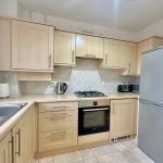 Modern kitchen with light wood cabinets and appliances.