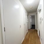 Bright hallway with wooden floor and white doors.