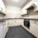 Modern kitchen with white cabinets and appliances.