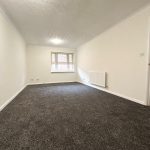 Empty living room with grey carpet and window.
