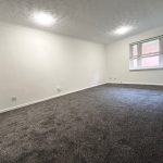 Spacious empty room with grey carpet and window.