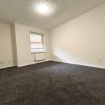Empty carpeted room with window and radiator