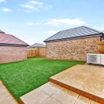 Brick house with grassy garden and patio area.