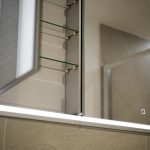 Illuminated bathroom cabinet with mirrored door open.