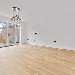 Spacious room with wooden floor and garden view.