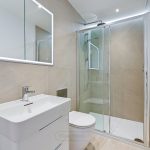 Modern bathroom with glass shower and illuminated mirror.