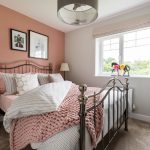 Cosy bedroom with pink accents and metal bed frame.