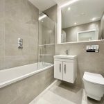 Modern bathroom with bathtub and mirrored cabinet.
