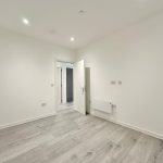Minimalist empty room with open door and light floors.