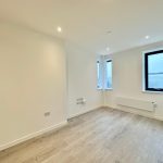 Empty room with wooden floor and large windows.