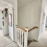 Upstairs hallway with open doors and white railings.