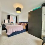 Modern bedroom with double bed and mirrored wardrobe.