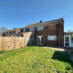 Sunny back garden with brick house view.