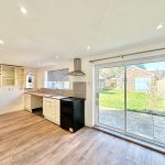Modern kitchen with garden view through glass doors.