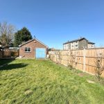 Sunny garden with shed and blue sky.
