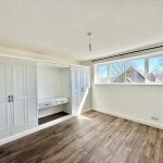 Bright room with wooden floor and wardrobe, large window.