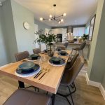 Modern dining room with set table and green walls.