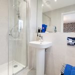 Modern bathroom with glass shower and white sink.