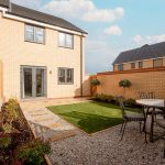 Modern brick house with garden and patio furniture.