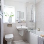 Modern beige tiled bathroom with shower and plants.
