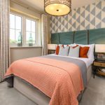 Modern bedroom with accent pillows and orange blanket.