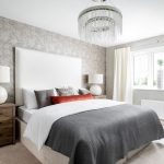 Modern bedroom with chandelier and large window.
