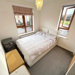 Compact bedroom with bed, windows, and storage.