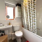 Bathroom with sink, toilet, and colourful shower curtain.