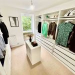 Spacious walk-in wardrobe with clothes and shoes.