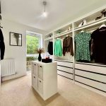 Modern walk-in wardrobe with shelves and hanging clothes.