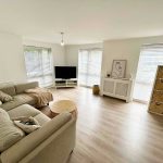 Modern living room with beige sofa and TV.