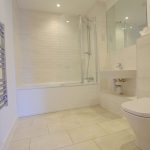 Modern bathroom with tiled flooring and shower.