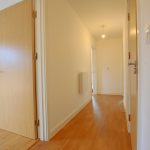 Bright empty hallway with wooden flooring.