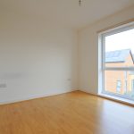 Empty room with wooden floor and window view.
