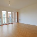 Spacious room with wooden floor and large windows.