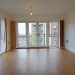 Bright empty room with large windows and wooden floor.