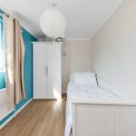Small bedroom with white furniture and blue wall.