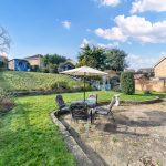 Sunny garden with patio furniture and shed.