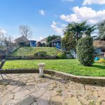 Sunny garden with patio and trees in spring.