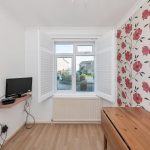 Room with floral wallpaper and open shutters.
