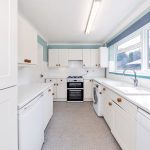 Bright kitchen with white cabinets and appliances.