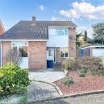 Detached brick house with front garden on sunny day.