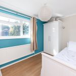 Bright bedroom with white furniture and blue walls.