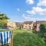Sunny garden view with houses and blue sky.