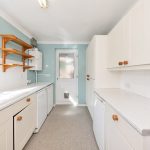 Modern white kitchen with appliances and shelving.